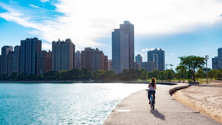 Chica monta en bicicleta a orillas del lago Michigan en dirección a los rascacielos de Chicago.