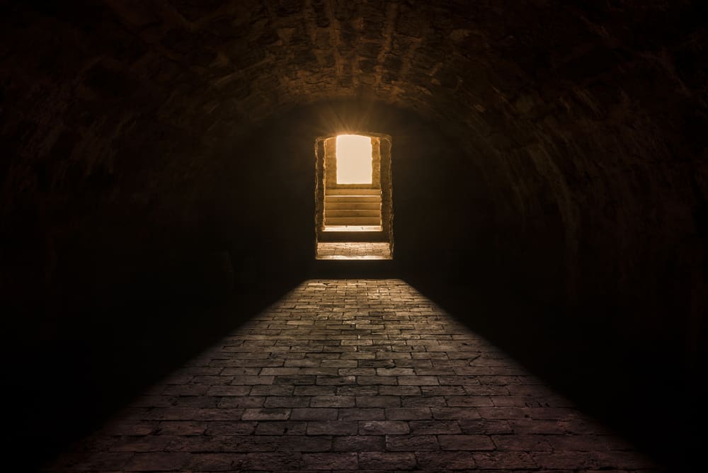 Tunnel with illuminated doorway at the end