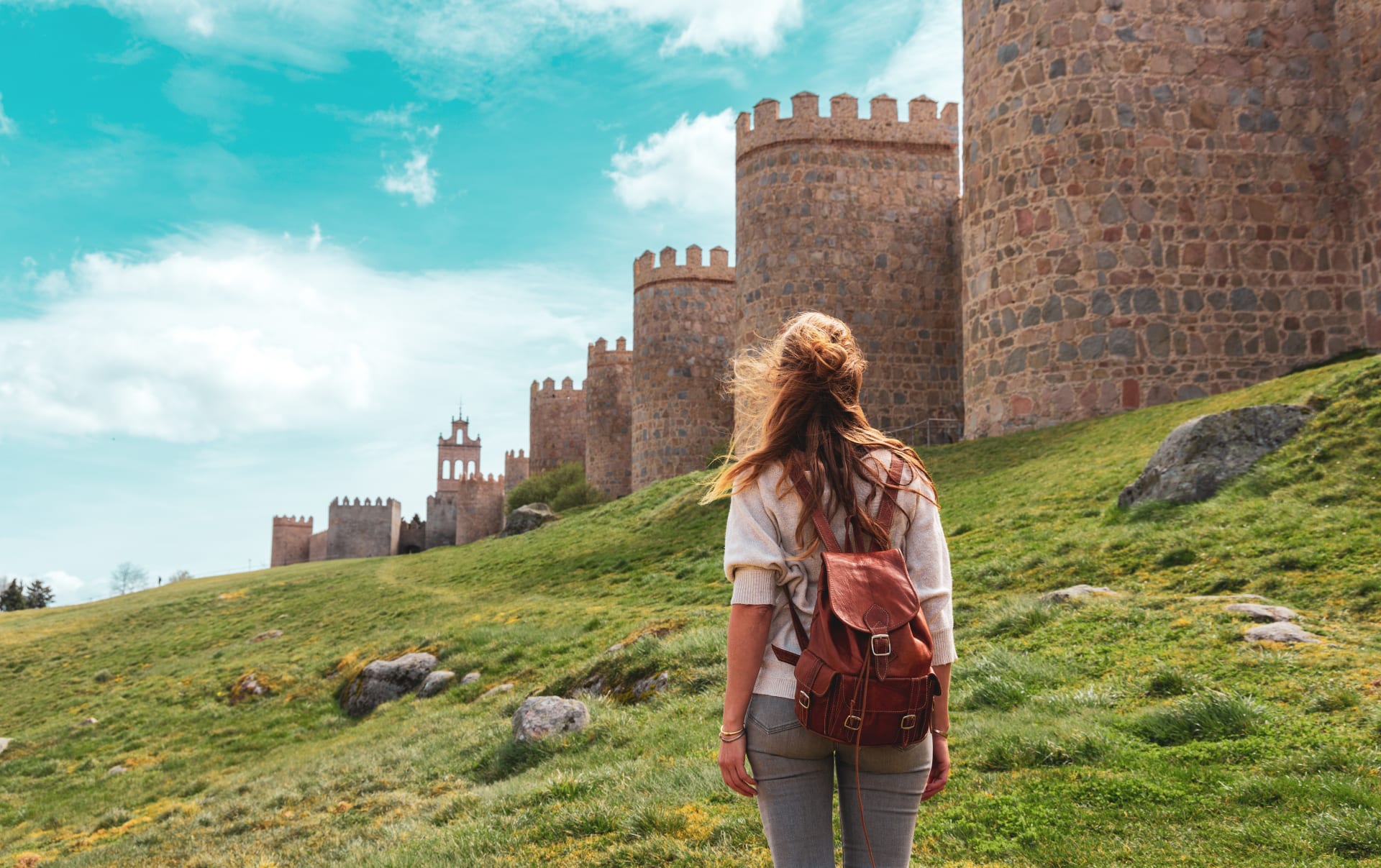 Mujer camina al lado de las murallas de Ávila, España. Las mejores escapadas desde Madrid.