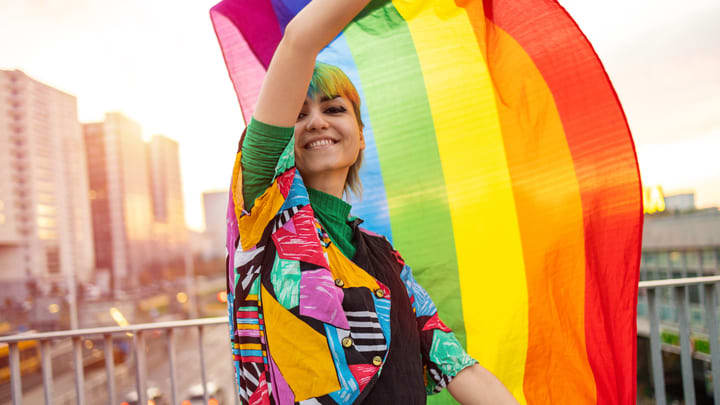 Persona che sventola una bandiera arcobaleno del Pride