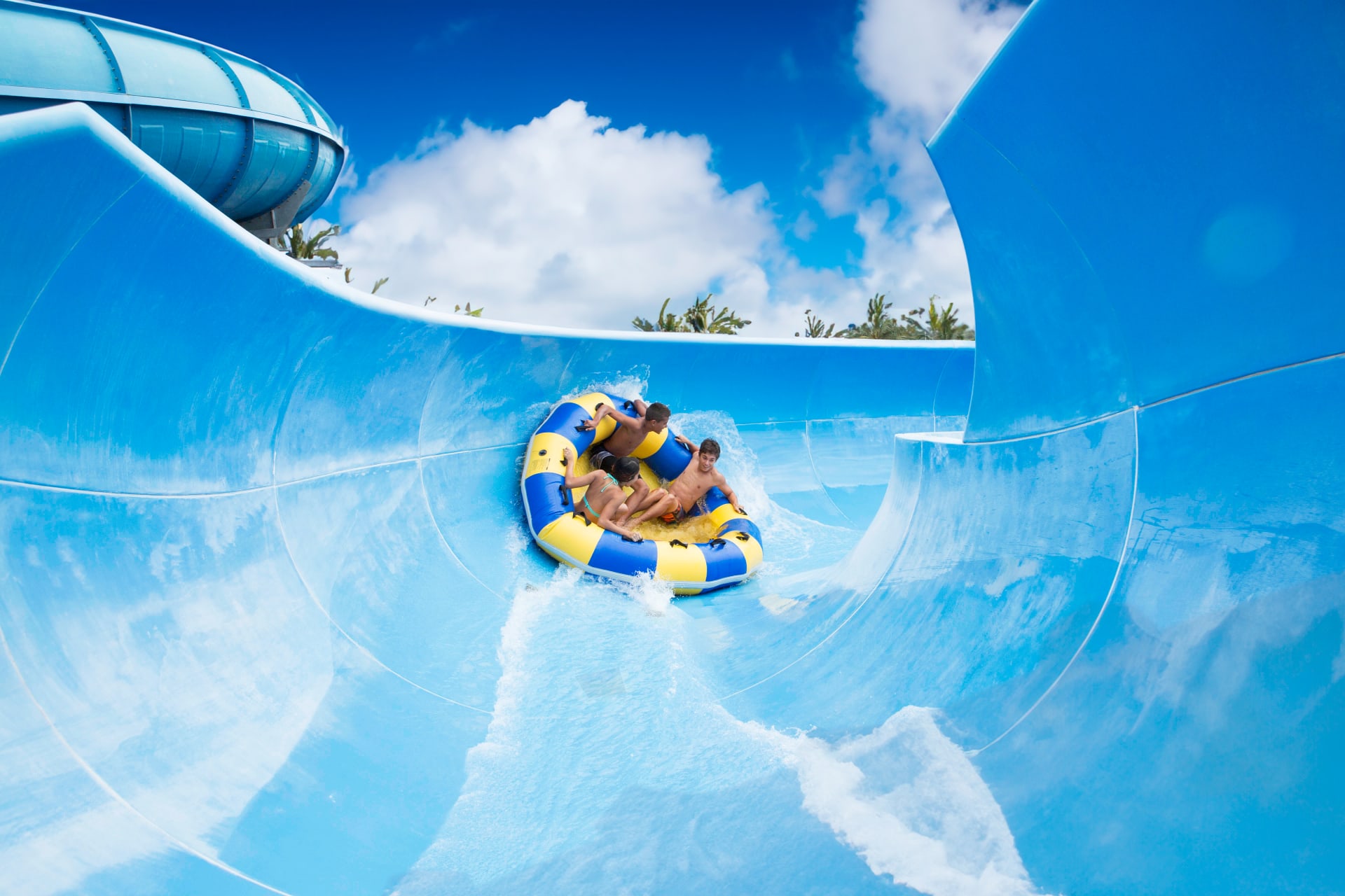 3 teens speeding down a waterslide.