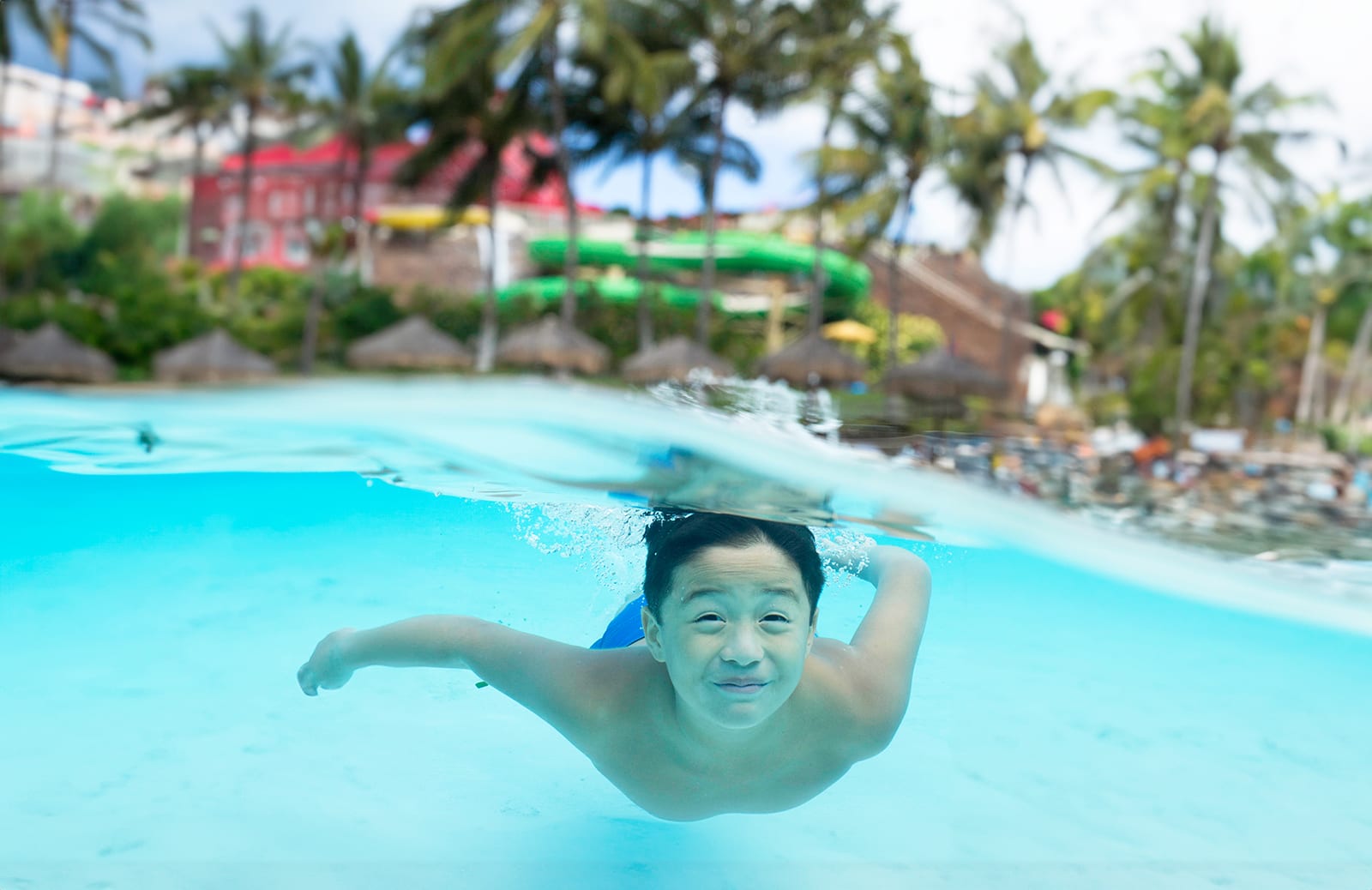 Boy underwater with a beachy background.