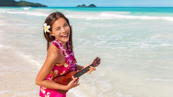 Hawaiian girl on the beach with ukelele and traditional lei garland
