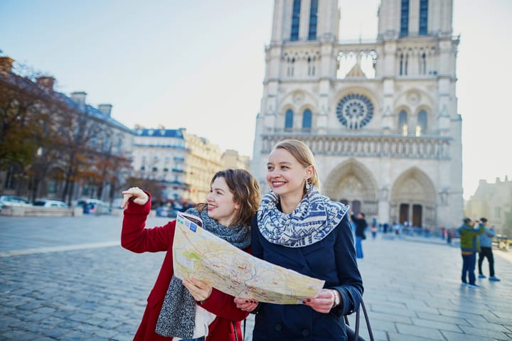Mujeres mirando plano frente a Notre Dame, París. Pase Explorer vs. Paris Pass de Go City.