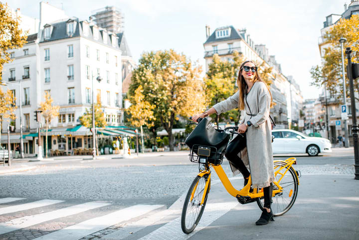Mujer en bicicleta en las calles de París. Guía de los planes que deberías evitar en París.