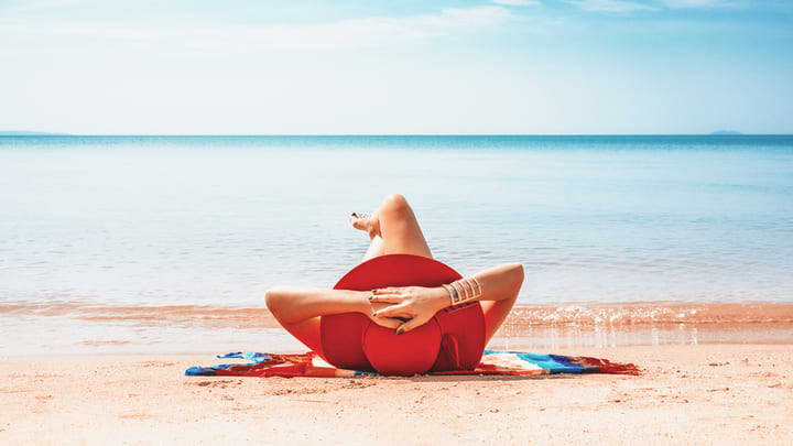 Frau mit Sonnenhut am Strand
