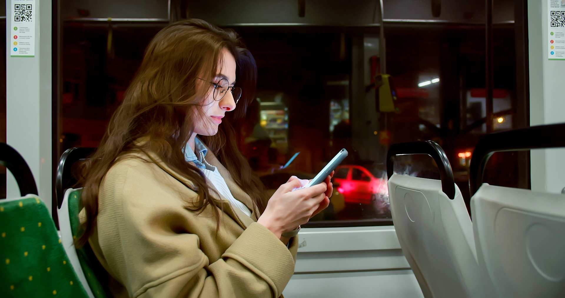 woman on her phone riding the bus at night