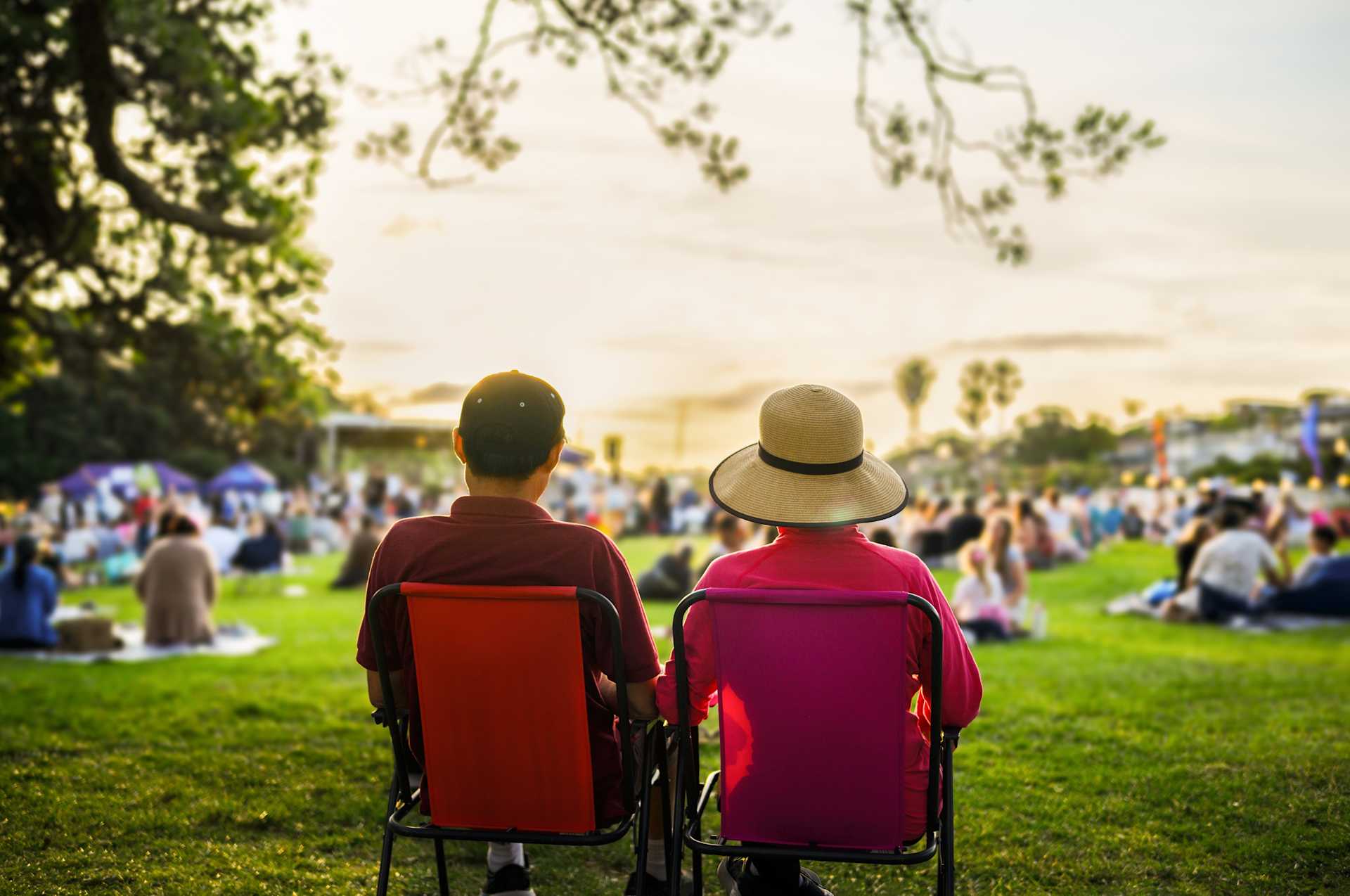 couple sitting on chairs in a park watching a performance 