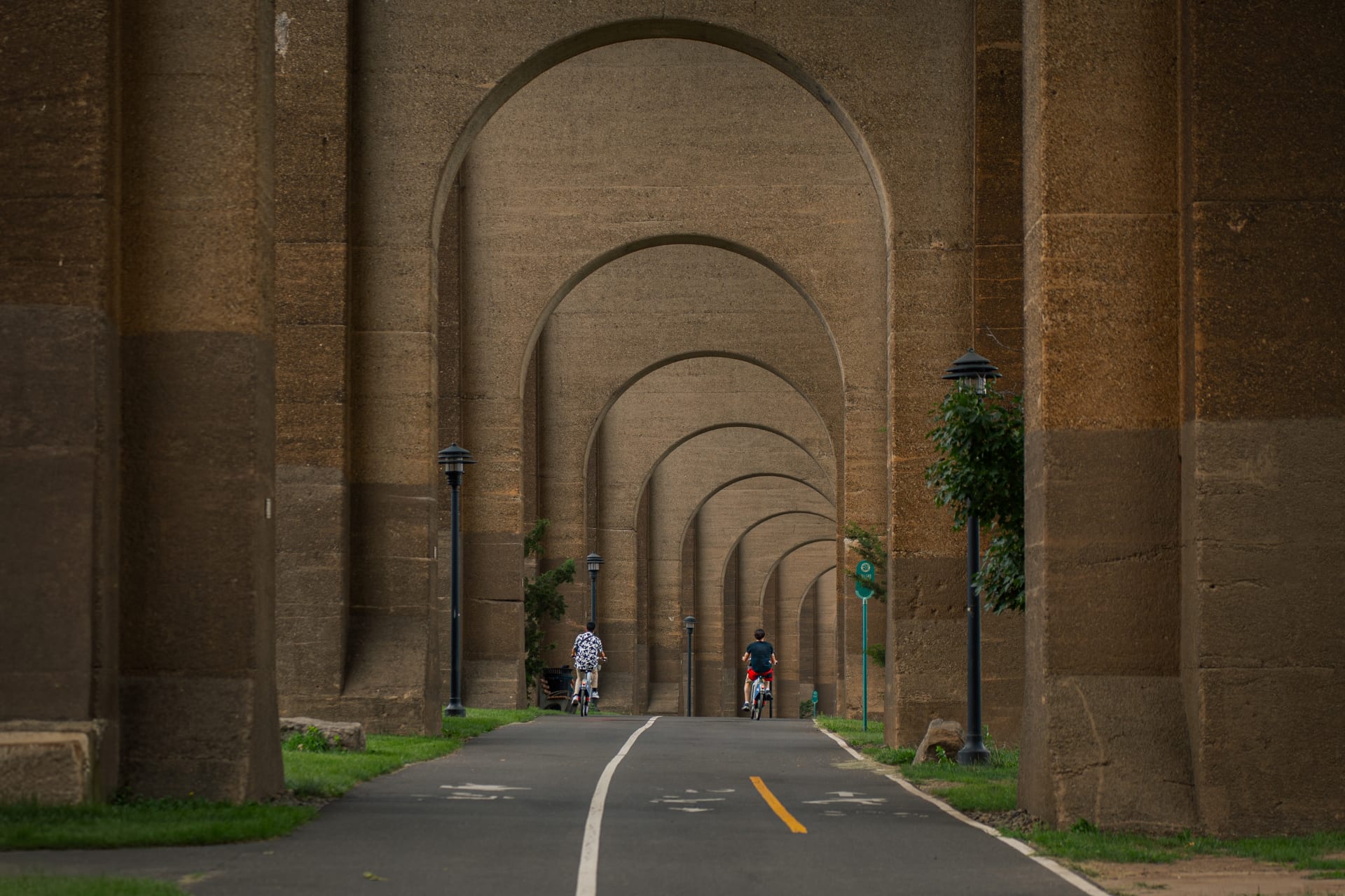 two-people-riding-bikes-underneath-bridge