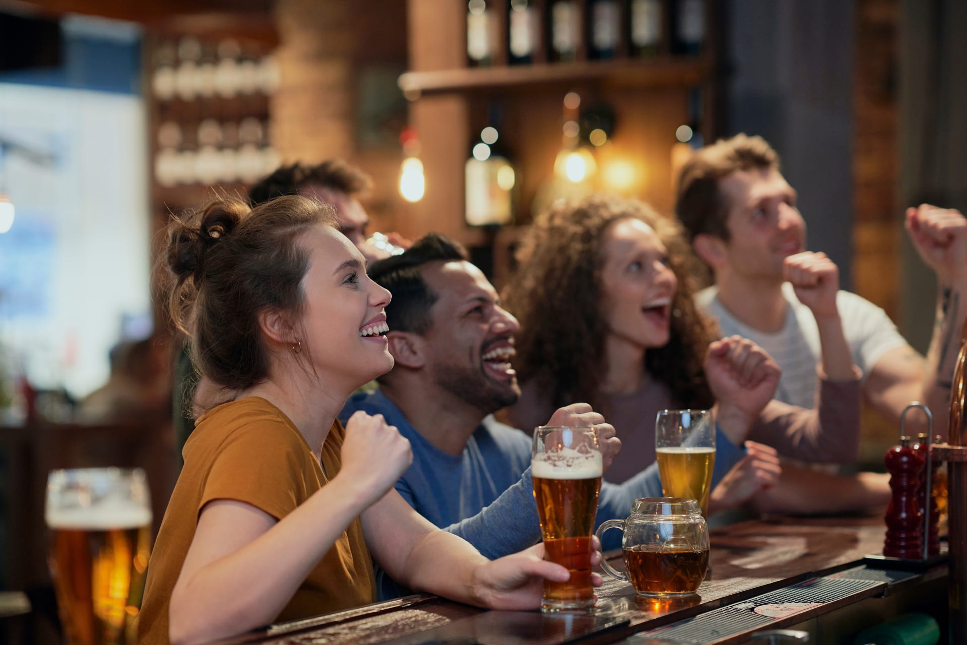 Grupo de chicos y chicas toman cerveza y animan a su equipo en un bar. Bares en Nueva York.