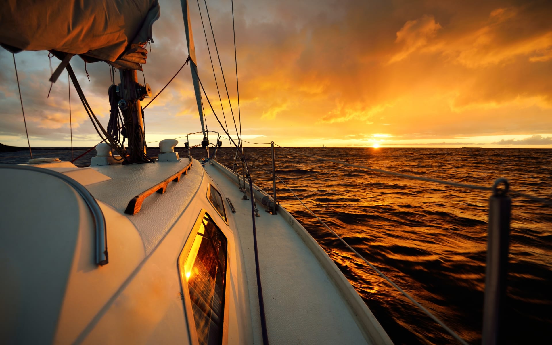 white-yacht-sailing-open-sea-sunset
