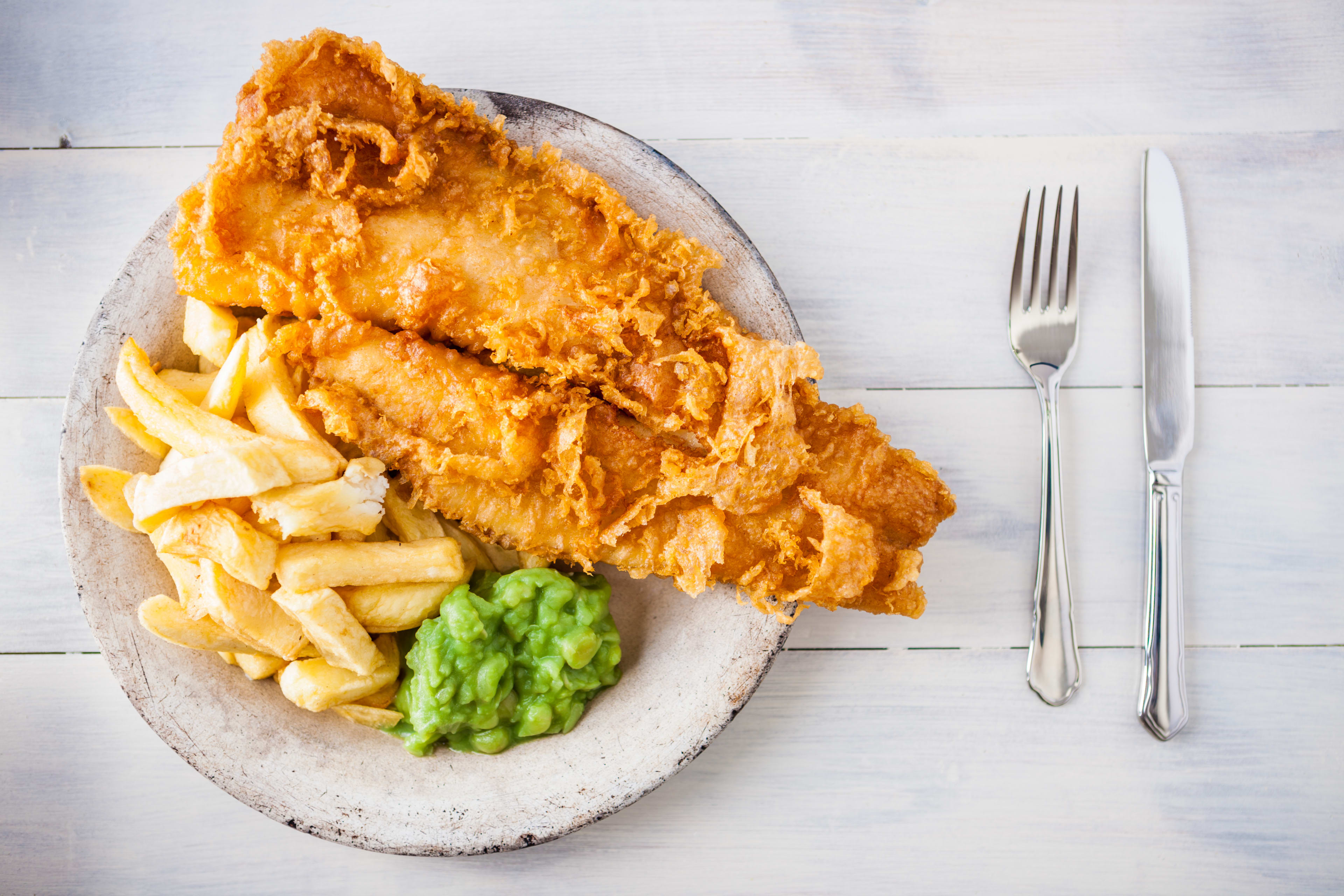 A plate of fish and chips with green mushy peas