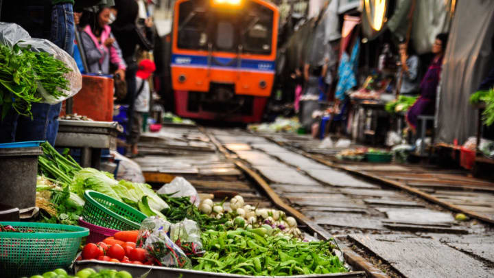 Train rolling through Maeklong Railway Market in Thailand