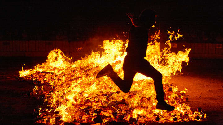 Person leaping over a beach bonfire