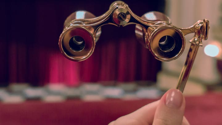 Woman's hand holding opera glasses in the auditorium