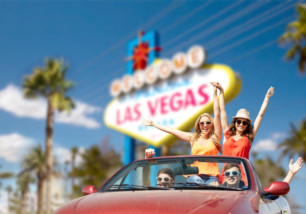 Carful of friends driving past the famous 'Welcome to Fabulous Las Vegas' sign