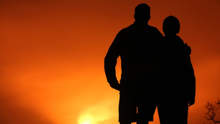 Hikers silhouetted against a lava-filled crater on Hawaii's Kilauea volcano