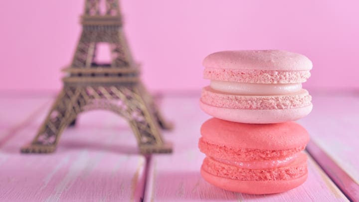 Pink macarons in front of a small model of the Eiffel Tower