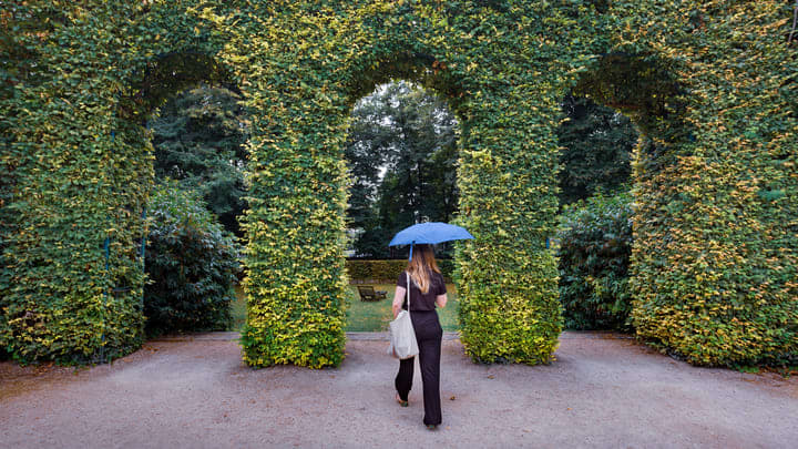 Woman with a parasol walking in the gardens of the Rodin Museum in Paris