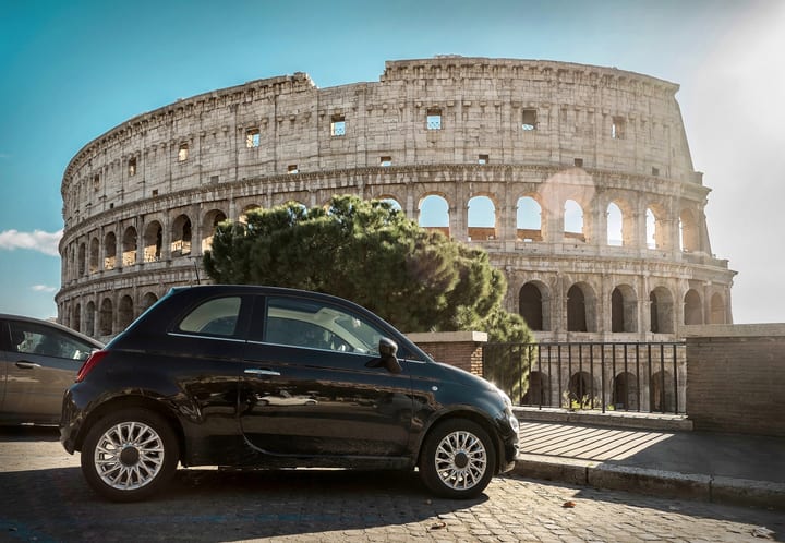 Coche negro aparcado frente al Coliseo de Roma. Alquiler de coche en Roma.