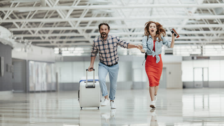 Couple running through the airport to catch a flight