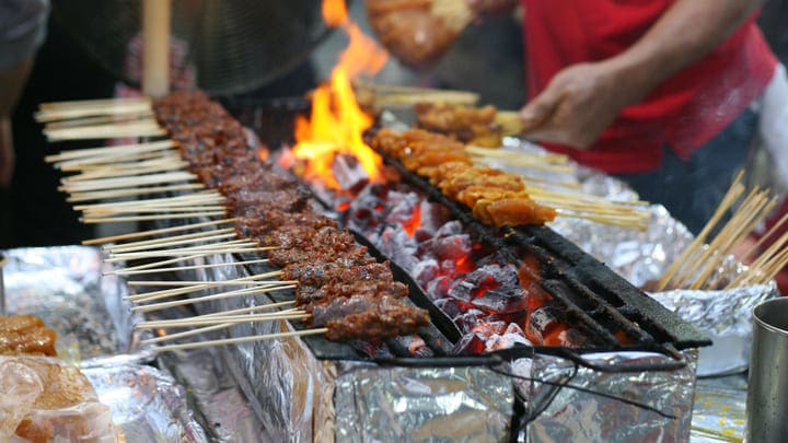 Satay chicken and pork cooking at a traditional Singapore street stall