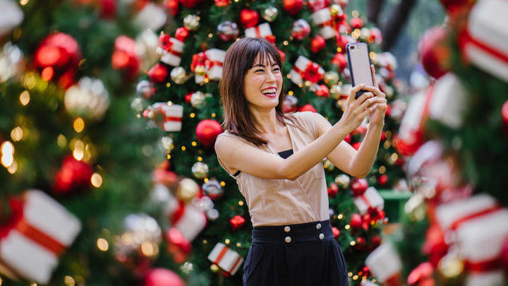 Woman taking a selfie next to a Christmas tree