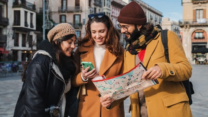 Friends consulting their phones and a map on vacation