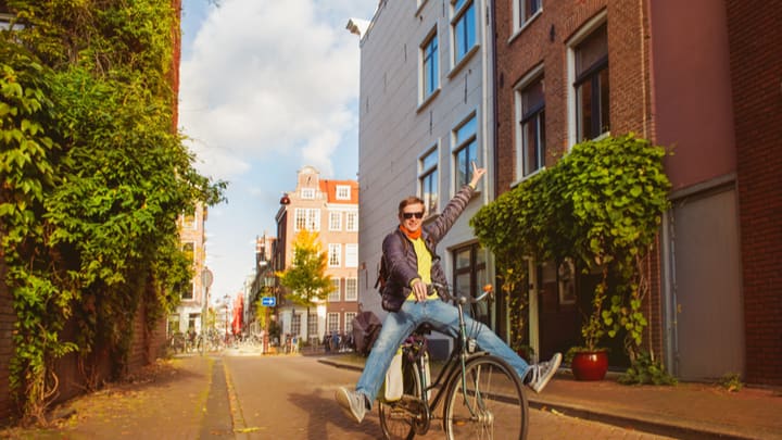 Image of City, Neighborhood, Road, Street, Urban, Adult, Male, Man, Person, Plant, Bicycle, Vehicle, Cycling,