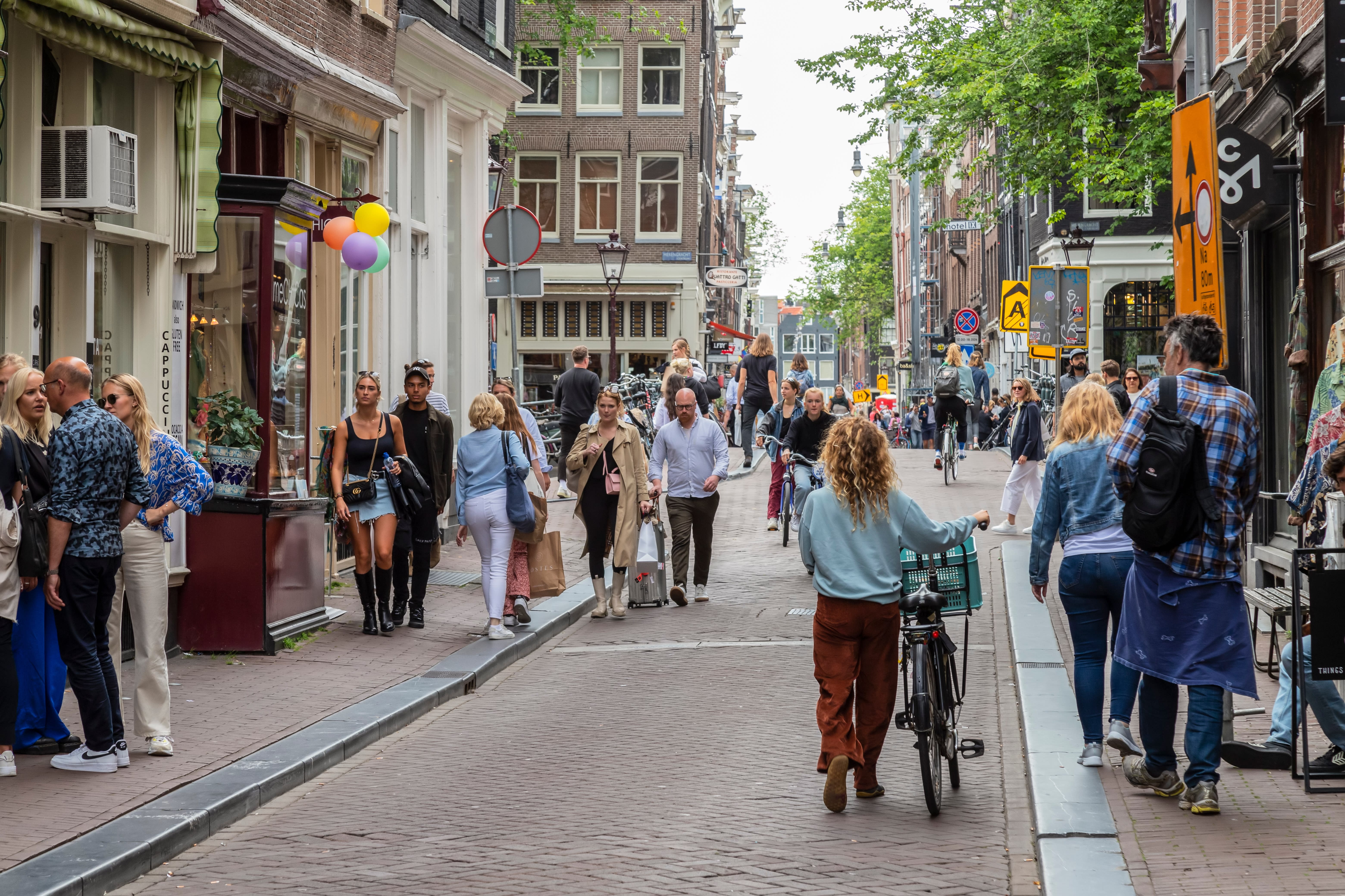 Image of City, Road, Street, Urban, People, Person, Path, Handbag, Backpack, Adult, Female, Woman, Male, Man, Neighborhood, Shoe, Plant, Bicycle, Vehicle, 