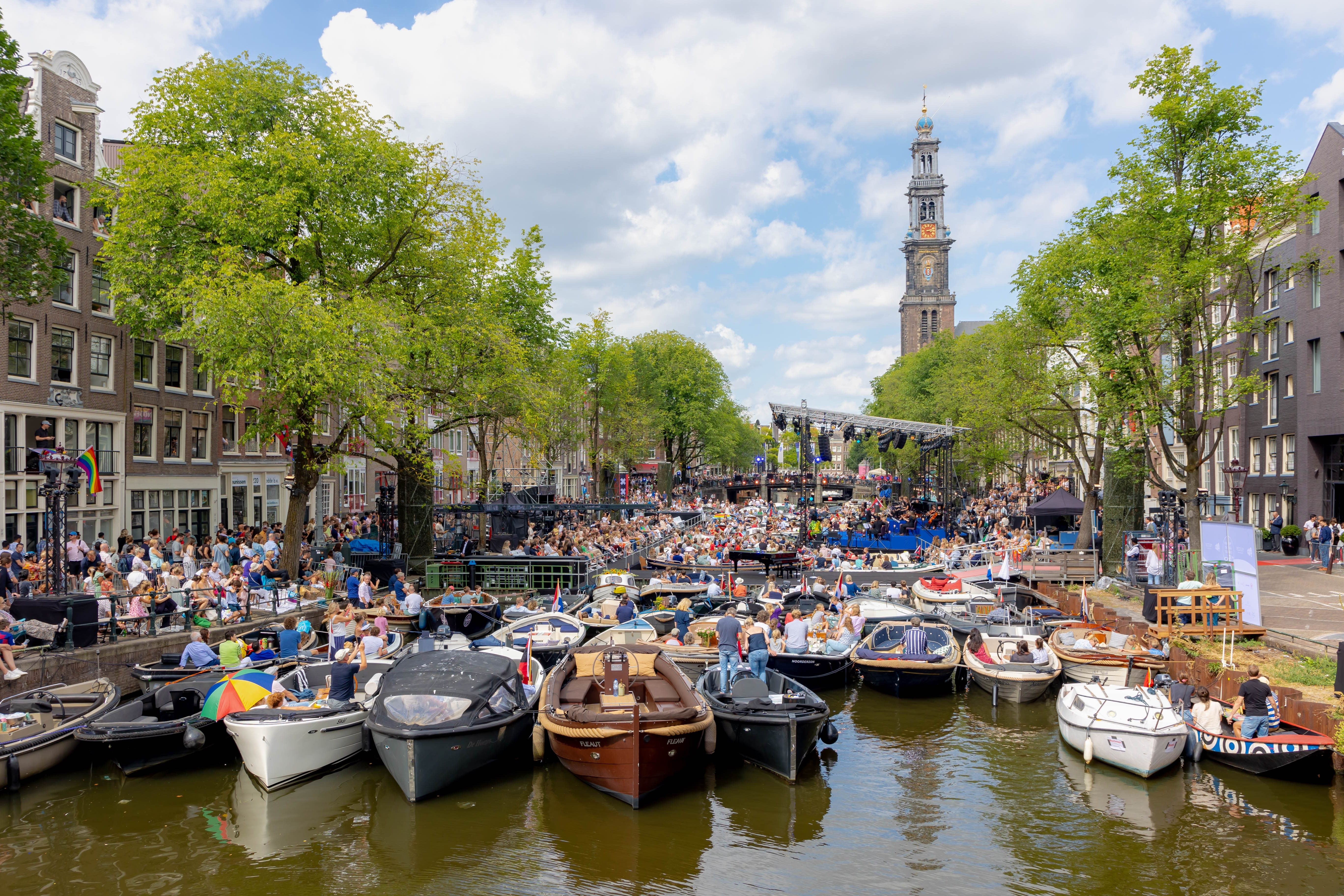 Image of Water, Waterfront, Boat, Vehicle, Harbor, Pier, Person, Plant, City, Urban, Nature, Outdoors, Scenery, Flag, Watercraft, 