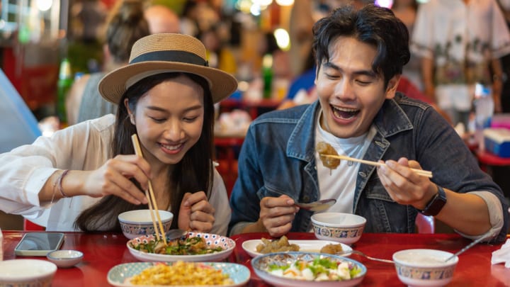 Image of Adult, Male, Man, Person, Dining Table, Female, Woman, Eating, Food, Hat, Chopsticks, 