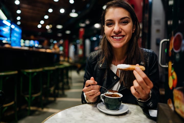 Image of Face, Happy, Head, Person, Smile, Indoors, Restaurant, Adult, Female, Woman, Beverage, Coffee, Coffee Cup, Cup, Dining Table, 