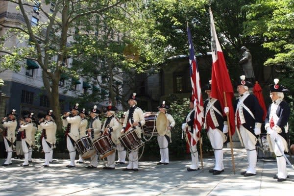 Image of People, Person, Glove, Marching, Adult, Male, Man, Flag, Hat, Shoe, Group Performance, Music, Music Band, Musical Instrument, Musician, Performer, 