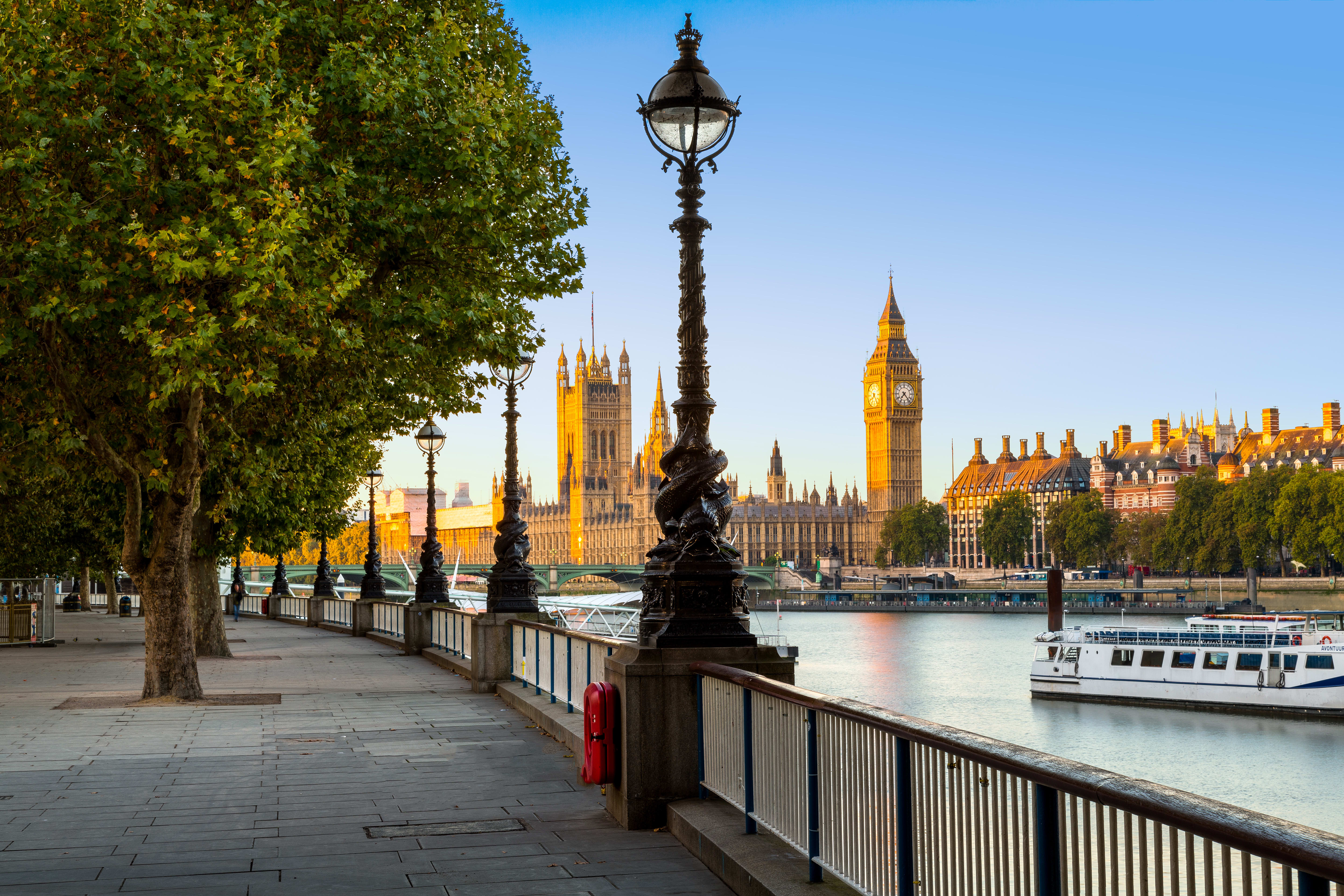 Image of Water, Waterfront, City, Spire, Tower, Metropolis, Urban, Nature, Outdoors, Scenery, Path, Boat, Vehicle, Clock Tower, Railing, Cityscape, Pier, Watercraft, Person, Sidewalk, 