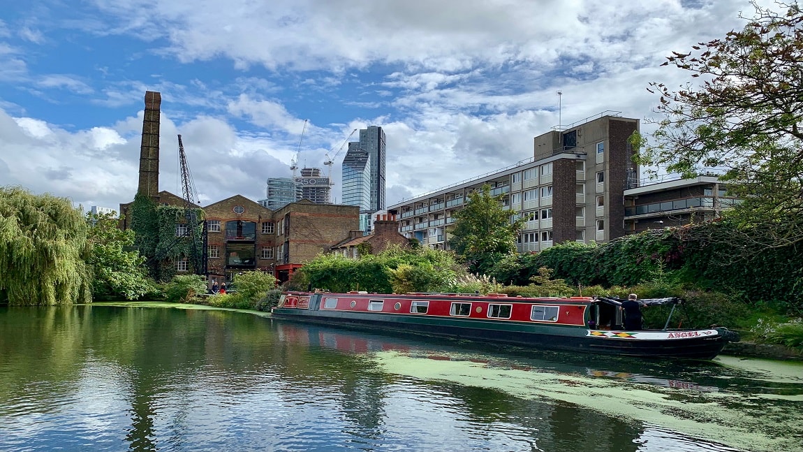 Image of City, Canal, Outdoors, Water, Urban, Cityscape, Boat, Vehicle, Nature, Scenery, Person, Watercraft, Waterfront, Neighborhood, Barge, Path, Towpath, Metropolis, 