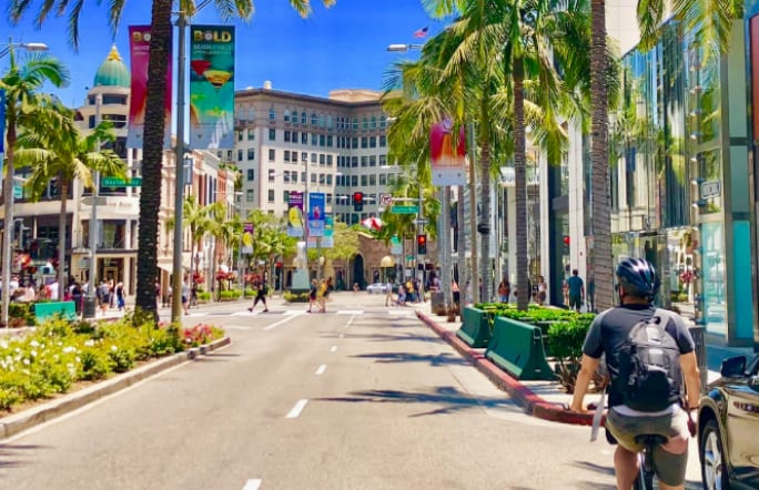 Image of City, Urban, Road, Street, Neighborhood, Downtown, Adult, Male, Man, Person, Helmet, Car, Vehicle, Path, Traffic Light, Cityscape, 