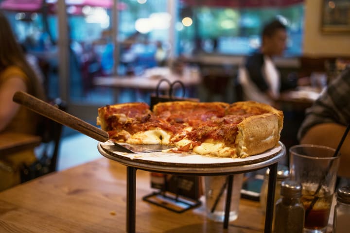 Image of Food, Pizza, Cup, Indoors, Restaurant, Cutlery, Boy, Child, Male, Person, Dining Table, Furniture, Table, Adult, Man, Female, Woman, 