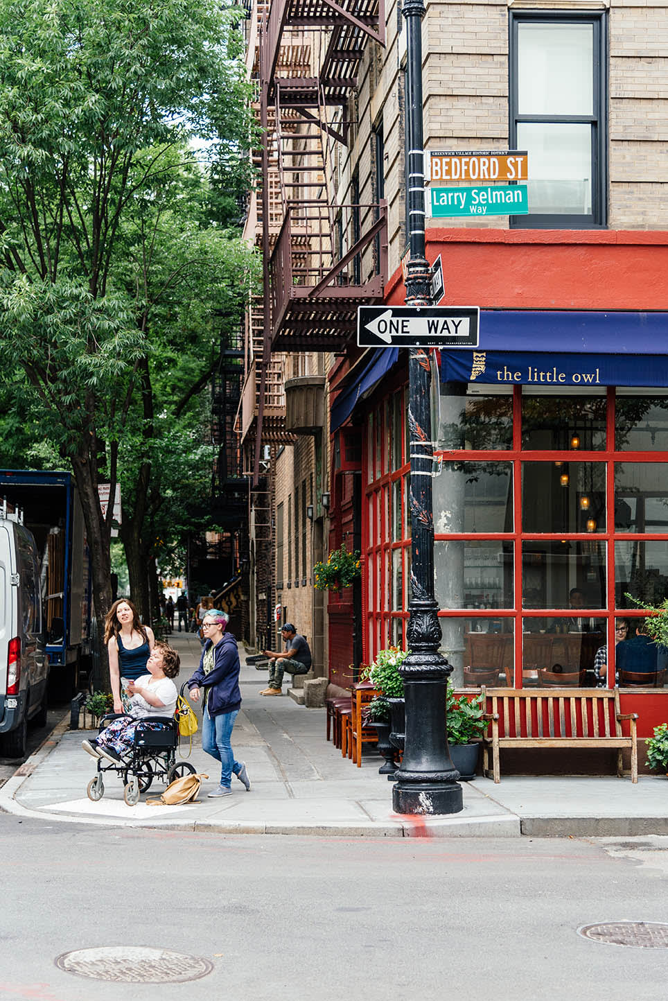 Image of City, Road, Street, Urban, Path, Sidewalk, Neighborhood, Adult, Female, Person, Woman, Bench, Furniture, Bag, Handbag, Baby, Alley, Walkway, Plant, Pants, Walking, Metropolis, Car, Vehicle, 