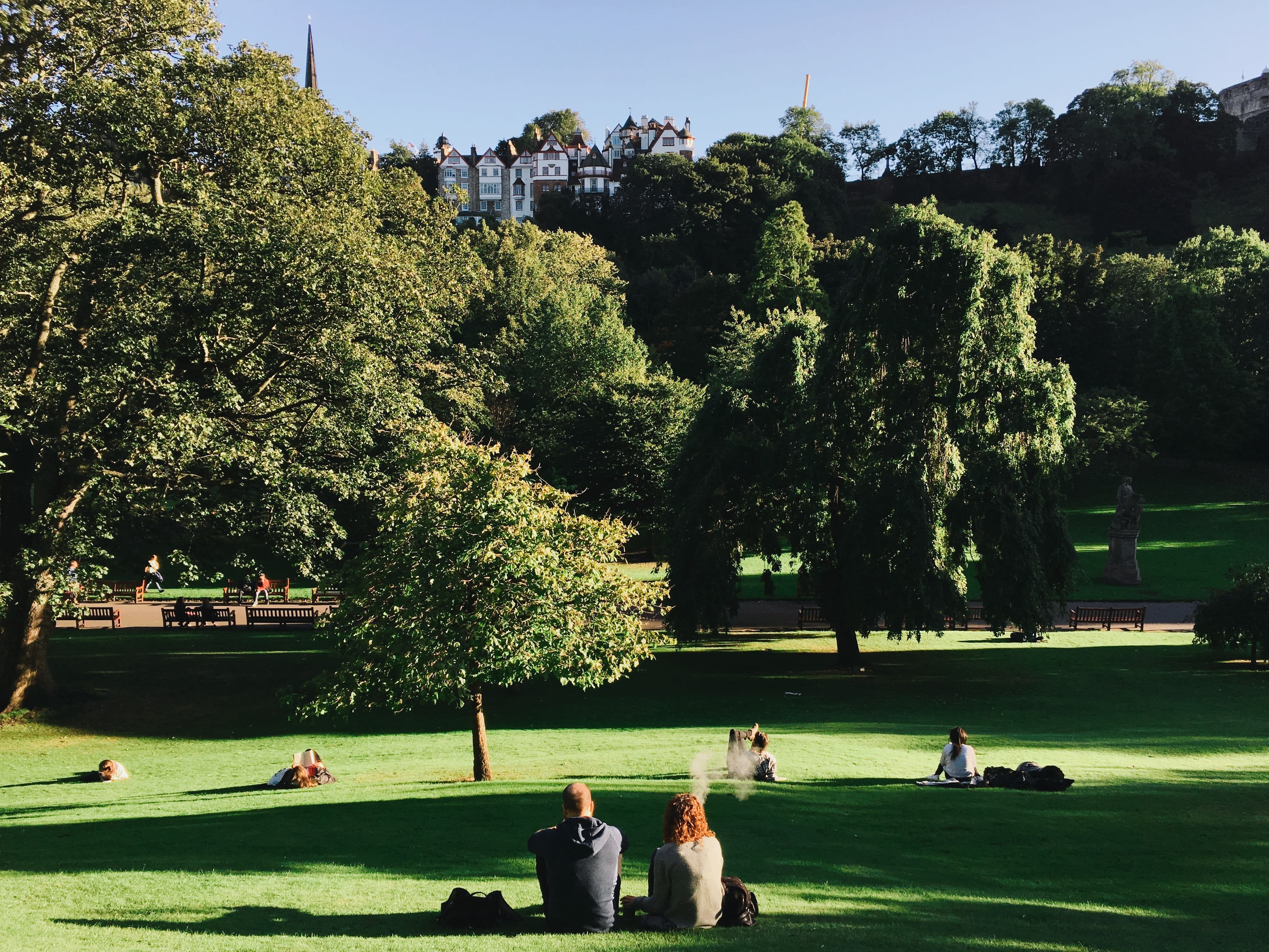 Image of Grass, Nature, Outdoors, Park, Grove, Land, Tree, Vegetation, Woodland, Lawn, Person, Bench, Furniture, Formal Wear, Suit, Handbag, 