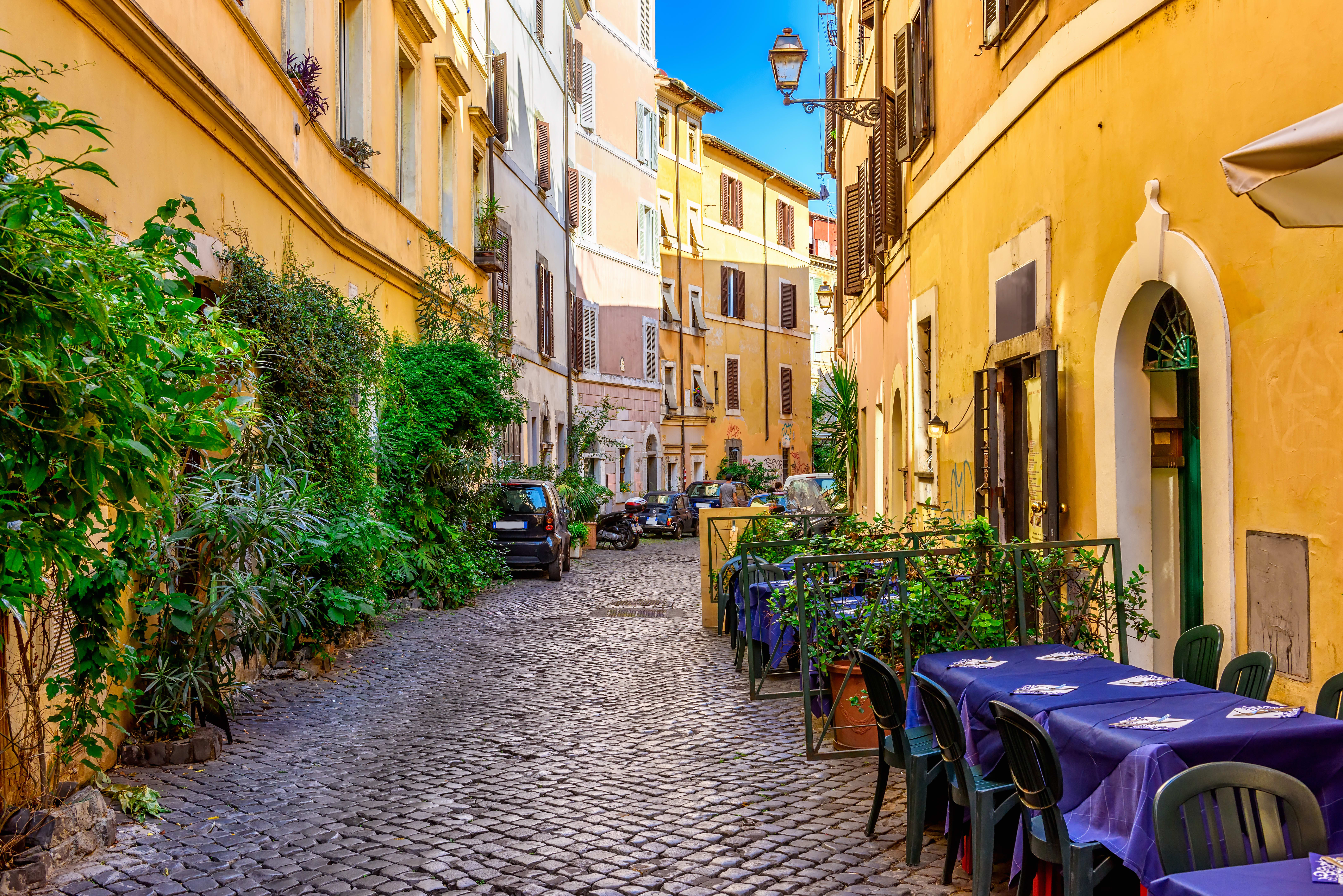 Image of Path, Road, City, Street, Urban, Cobblestone, Walkway, Neighborhood, Chair, Furniture, Dining Table, Table, Car, Flagstone, Person, Motorcycle, Plant, 