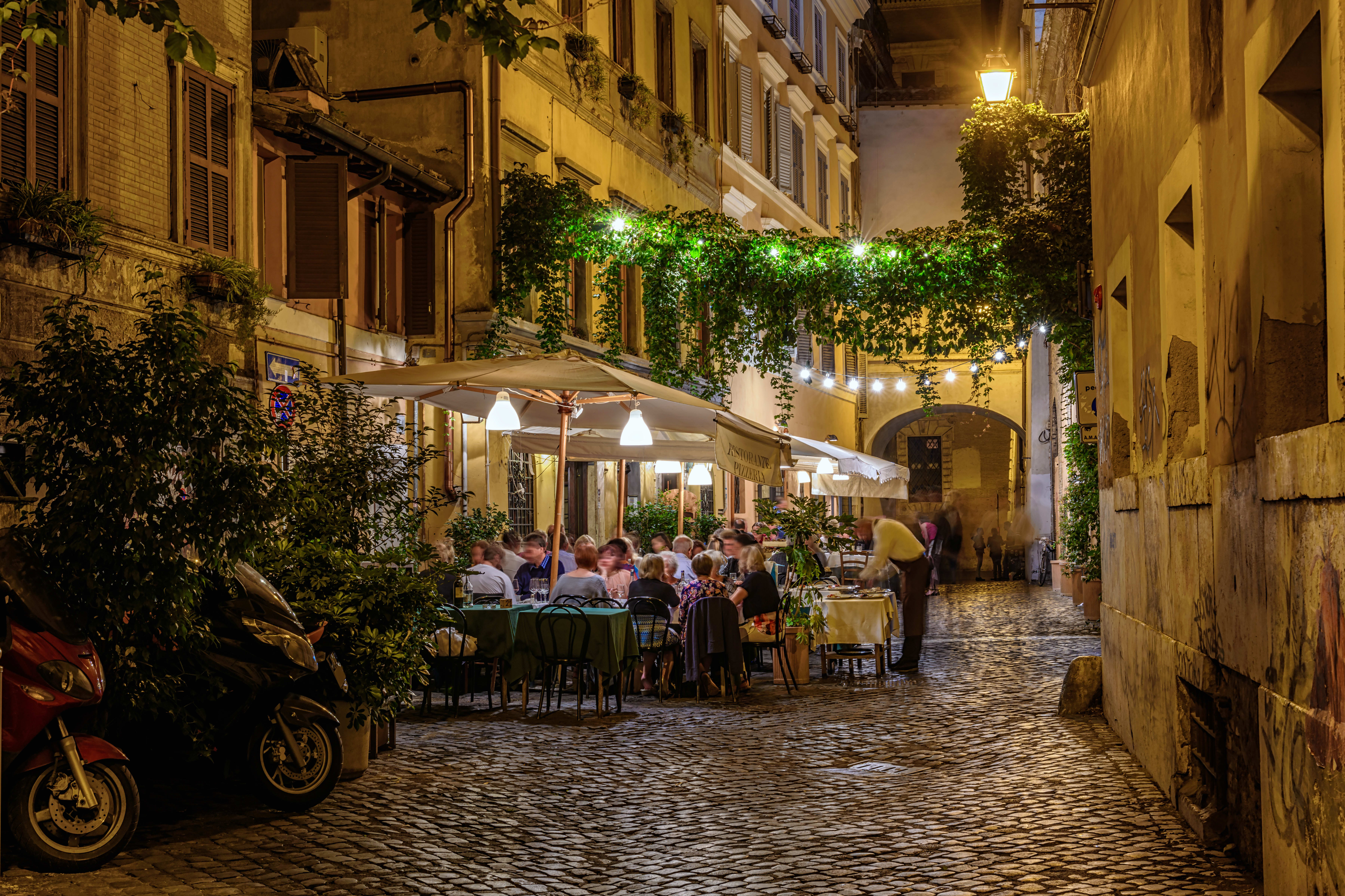 Image of Path, City, Road, Street, Urban, Indoors, Restaurant, Walkway, Cobblestone, Person, Motorcycle, Vehicle, Chair, Furniture, Cafe, Dining Table, Table, Cafeteria, 