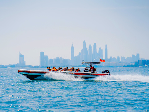 Speedboat cruising against the Dubai skyline at sunset.