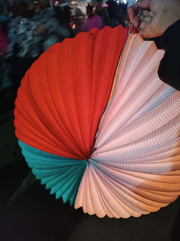 Arendrina en papier plissé aux couleurs du drapeau malgache — blanc, rouge et vert — brandie dans la rue le soir de la fête de l'Indépendance