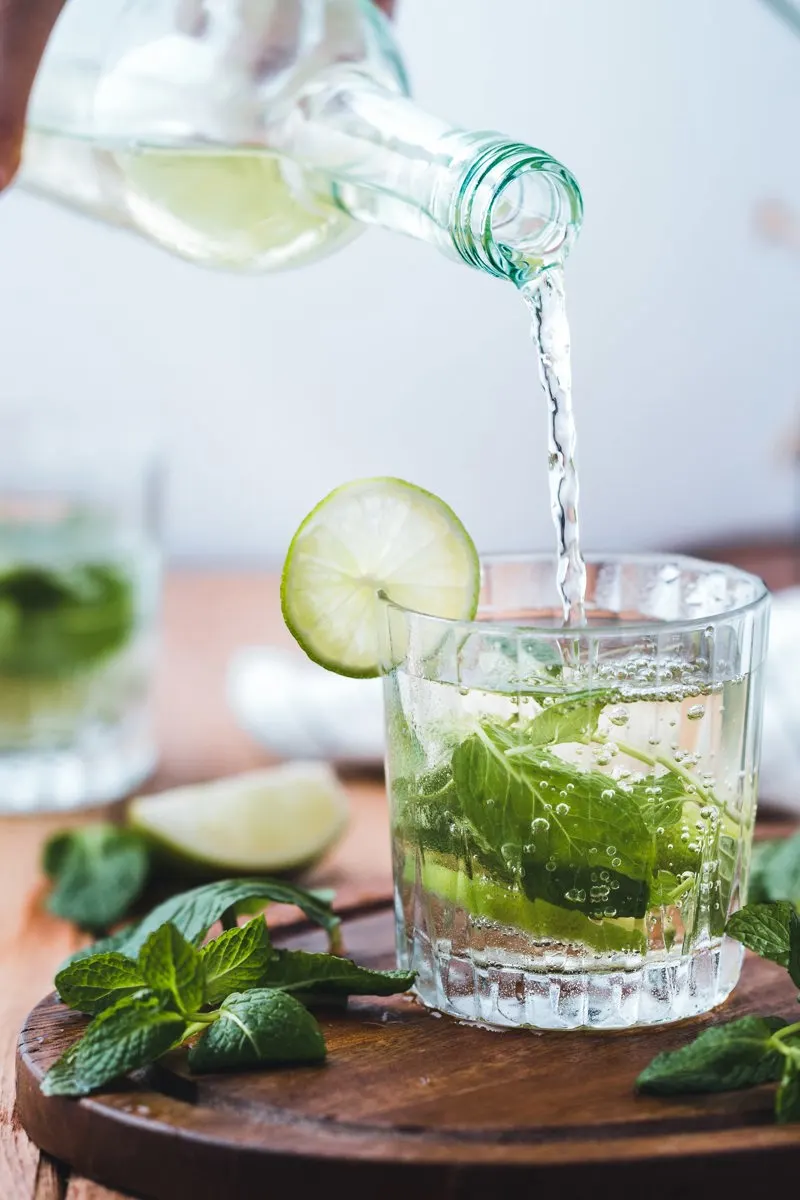 liquide clair versé dans un verre avec feuilles vertes