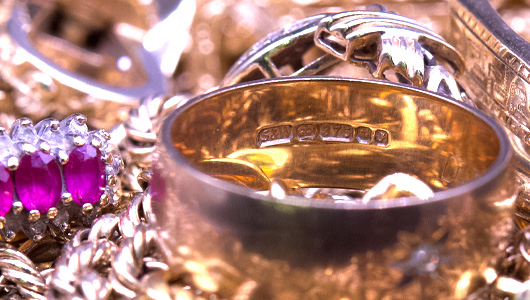 A pile of scrap gold, featuring a hallmarked 9ct gold ring, ready for valuation.