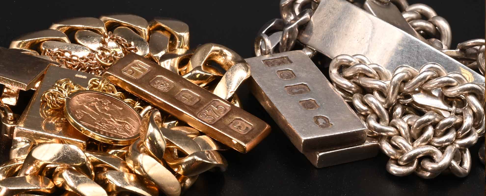 Two piles of jewellery. Gold on the left and silver on the right.