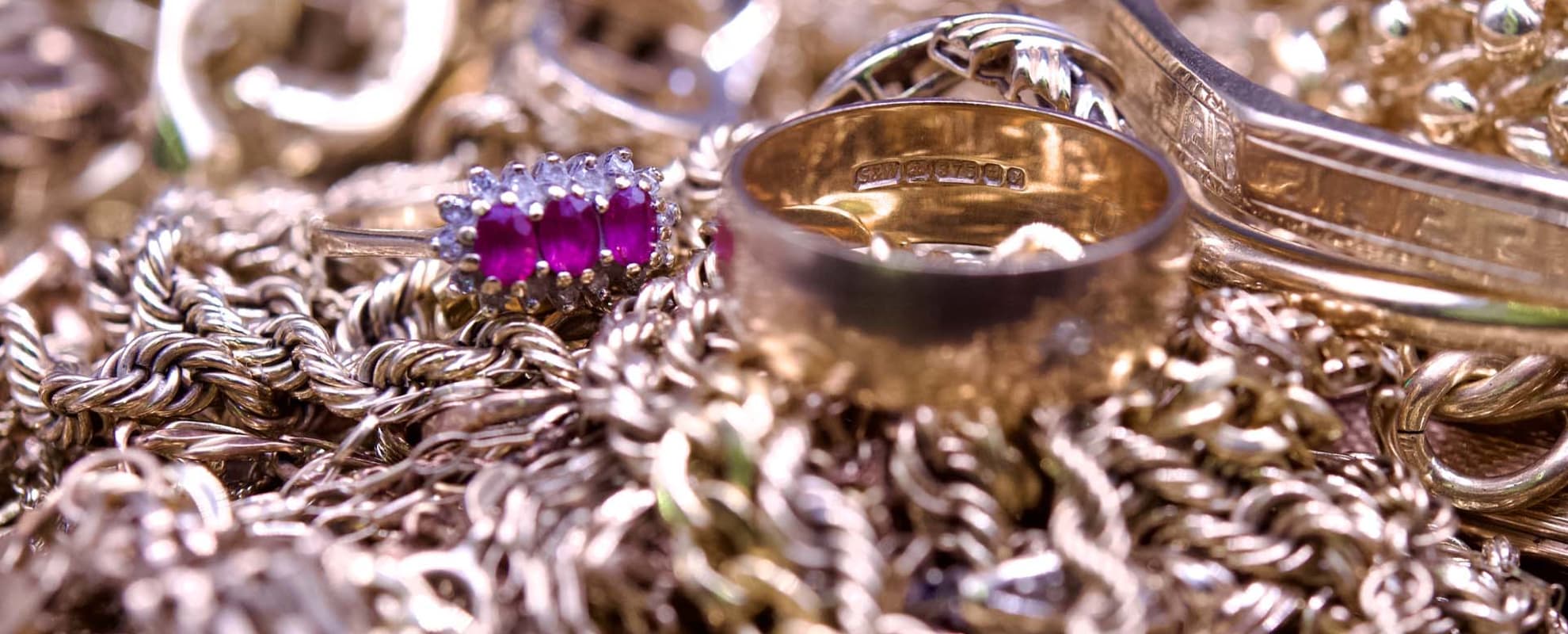 A pile of scrap 9ct gold with focus on a hallmark
