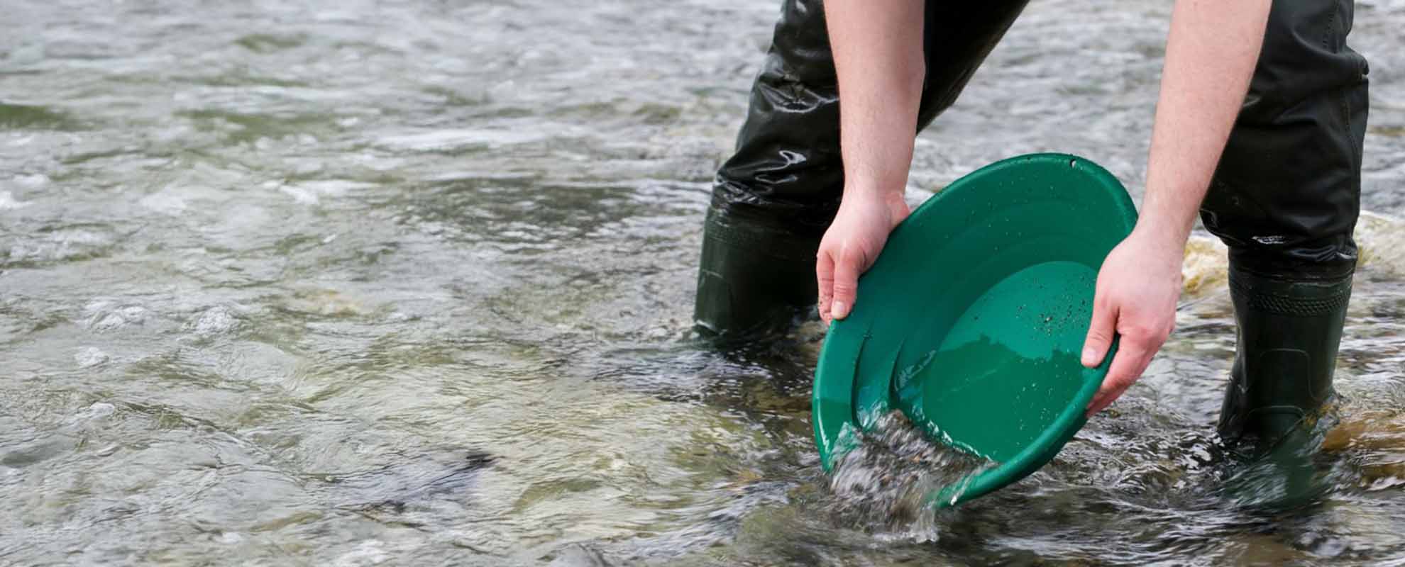 A gold prospector, stood in a Cornish river, panning for gold