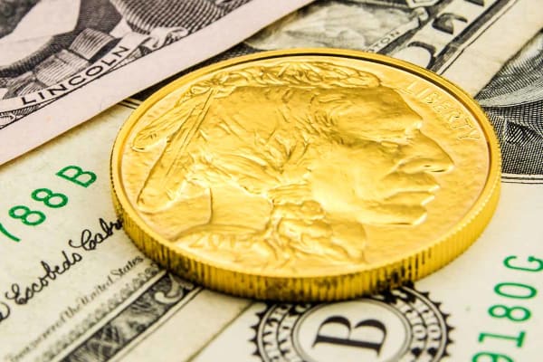 An American gold coin on top of some dollar bills
